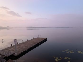 Pier on lake against sky during sunset