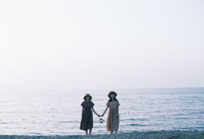 Women standing on sea against clear sky