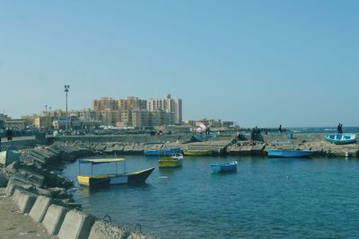 Boats moored in river against clear blue sky