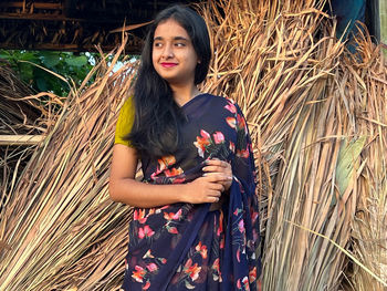 Portrait of young woman standing amidst plants