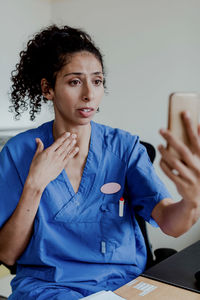 Worried nurse explaining on video conference while sitting in hospital