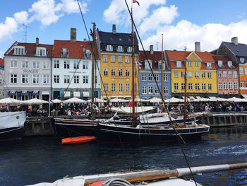 Sailboats moored on river by buildings in city against sky