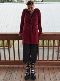 Portrait of woman standing against wooden railing