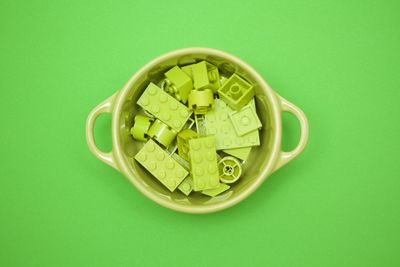 Directly above shot of toy blocks in container on green background