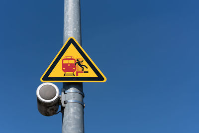 Low angle view of sign on pole against clear blue sky