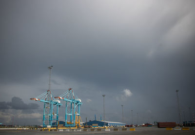 Cranes at commercial dock against sky