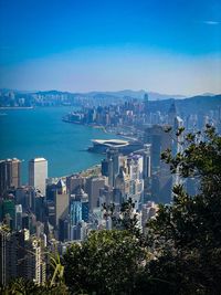 High angle view of city by sea against blue sky