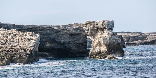 Rocks in sea against clear sky