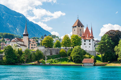 Buildings by river against sky