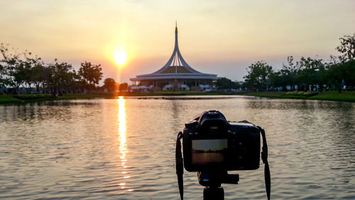 Reflection of camera in lake against sky during sunset