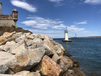 Lighthouse by sea against sky