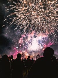 Silhouette people enjoying firework display at night