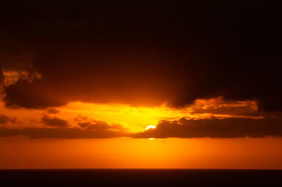 Scenic view of sea against dramatic sky during sunset