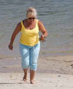 Woman holding crab while walking at beach