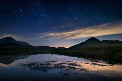 Scenic view of lake and mountains against sky at night