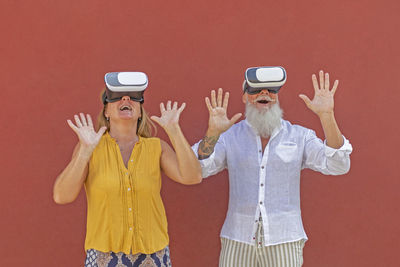 Rear view of man and woman using phone while standing against wall