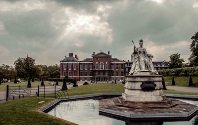Statue by building against sky