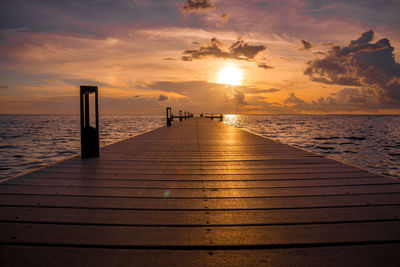 Pier over sea against sky during sunset