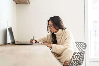 Young woman writing in diary and working at home office