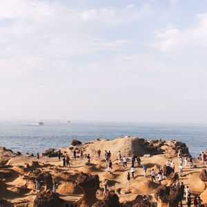 People relaxing on beach against sky