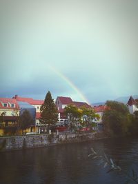 Scenic view of rainbow over town by river