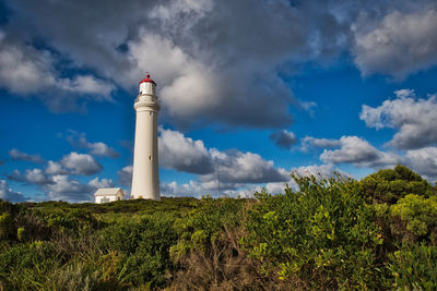 Low angle view of lighthouse by building against sky