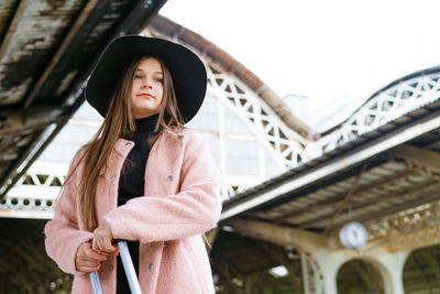 Young woman with suitcase on platform of station. traveler girl waiting