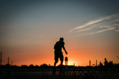 Silhouette man running on field against sky during sunset