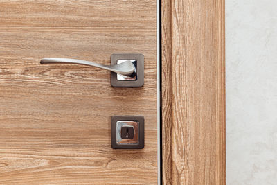 Modern metal door handle in a wooden interior door