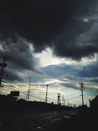 Low angle view of electricity pylon against cloudy sky