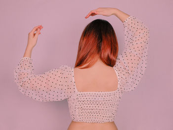 Rear view of woman standing against gray background