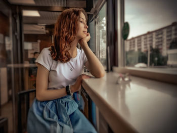 Young woman looking away while standing at home