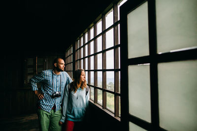 Full length of a young woman standing against window