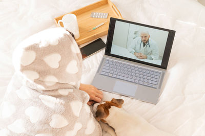 High angle view of woman talking with doctor on video call