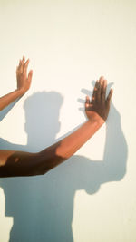 Cropped hands of woman with arms raised against sky