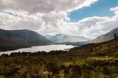 Scenic view of mountains and lake against cloudy sky