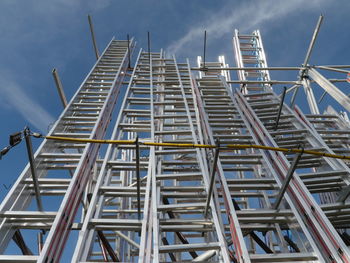 Low angle view of metallic ladders against sky