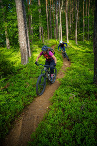 A young woman and a young man riding their mountain bikes on a singletrail near klagenfurt, austria.