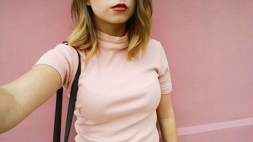 Midsection of young woman standing against wall