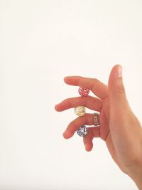 Cropped image of hand holding beads against white background