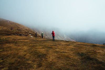 Friends standing on mountain during foggy weather