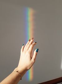 Close-up of hand holding rainbow over blurred background