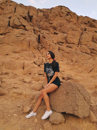 Full length of woman sitting on rock