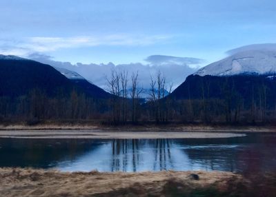 Scenic view of lake by mountains against sky