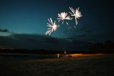 Low angle view of firework display over river on fourth of july