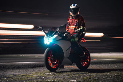 Rear view of man riding motor scooter on road