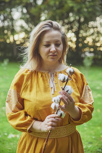 Portrait of smiling young woman standing by plants