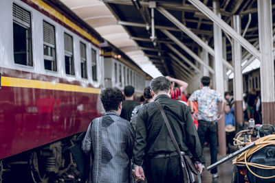 Rear view of people walking by train on platform