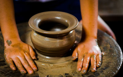 Cropped hands of child making pottery in workshop