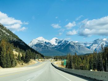 Road amidst snowcapped mountains against sky